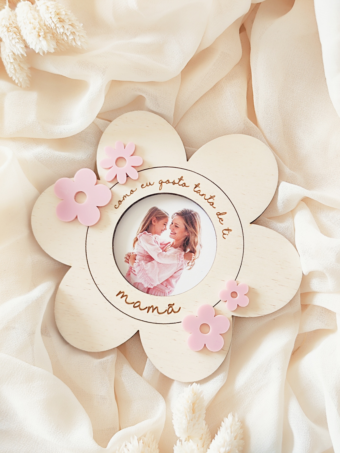 Moldura de madeira em forma de flor com texto em português e flores cor-de-rosa.