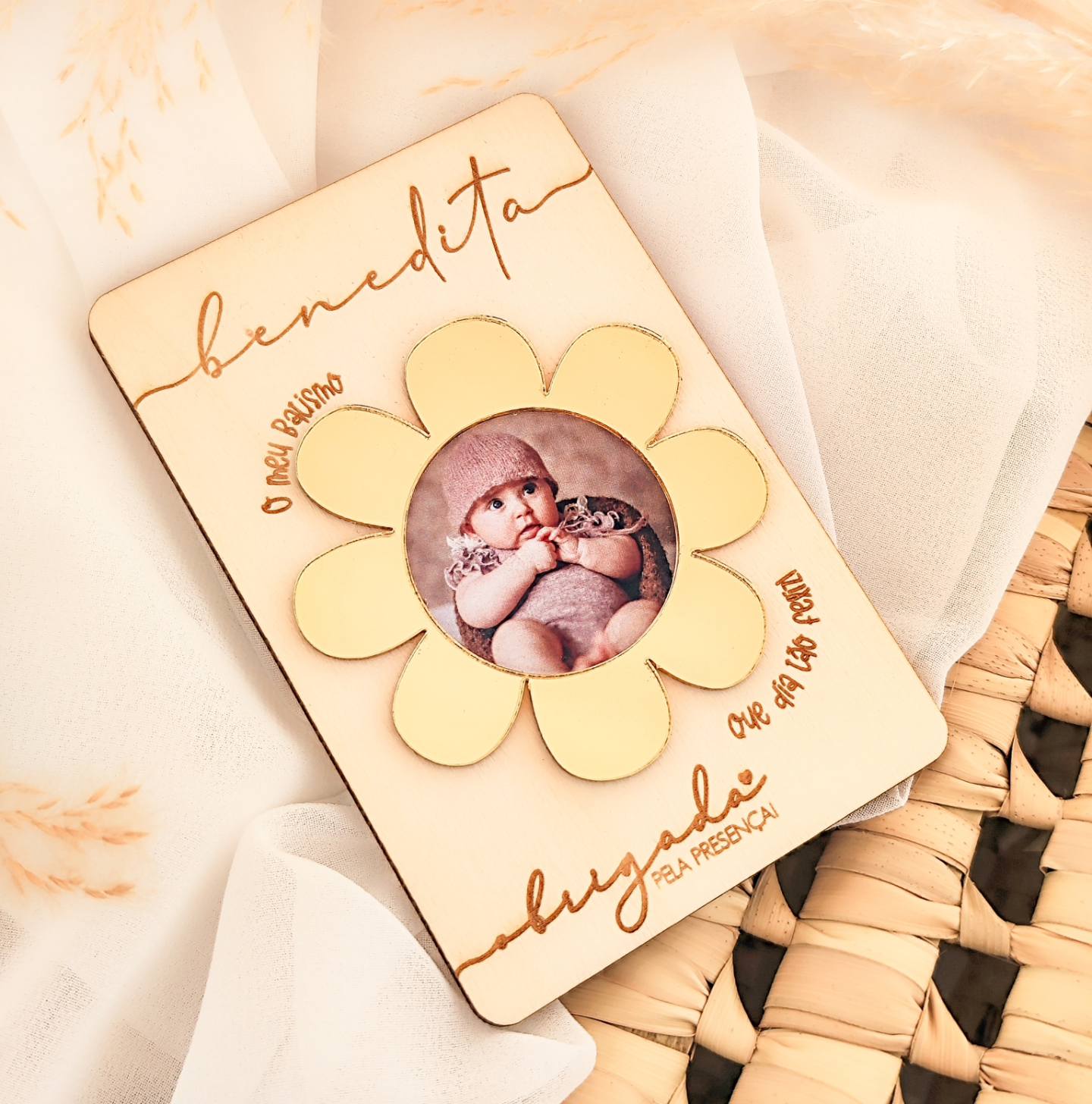 Placa de madeira com flor e foto de bebé, texto gravado em português.