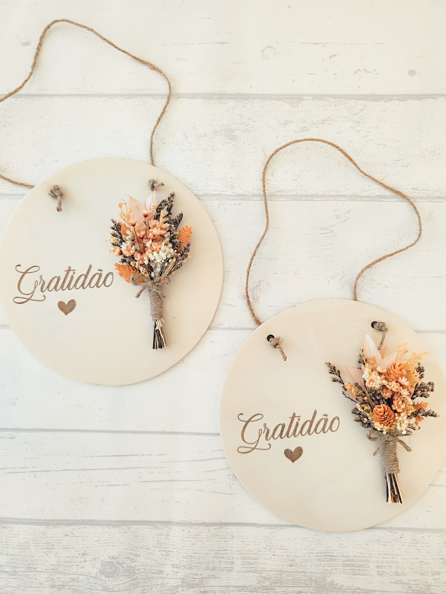 Dois discos decorativos brancos com flores secas e a palavra Gratidão pendurados