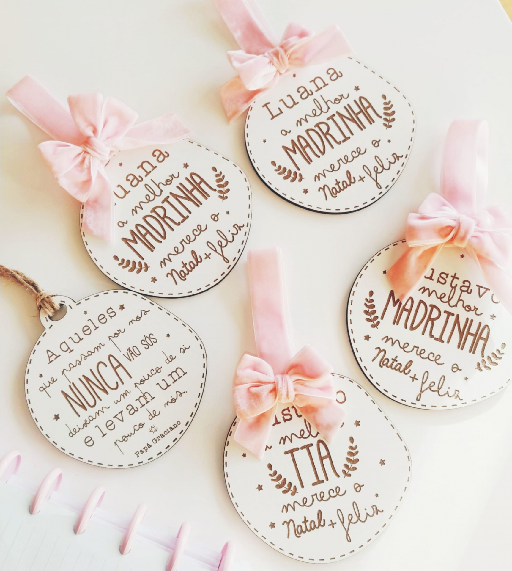 Ornamentos redondos em madeira com laços cor de rosa e textos em português para madrinhas e tias