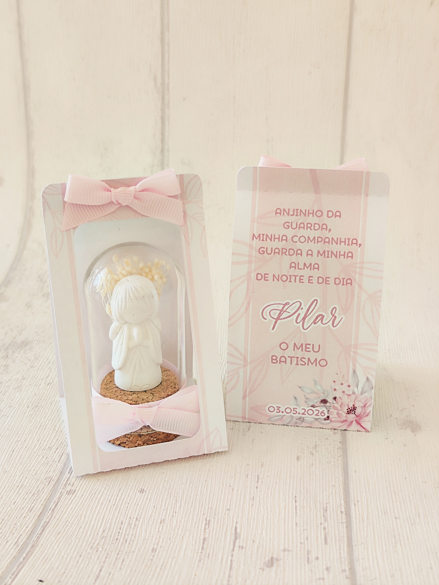 Miniatura de anjo branco em resina com laço rosa e cartão decorativo em fundo branco