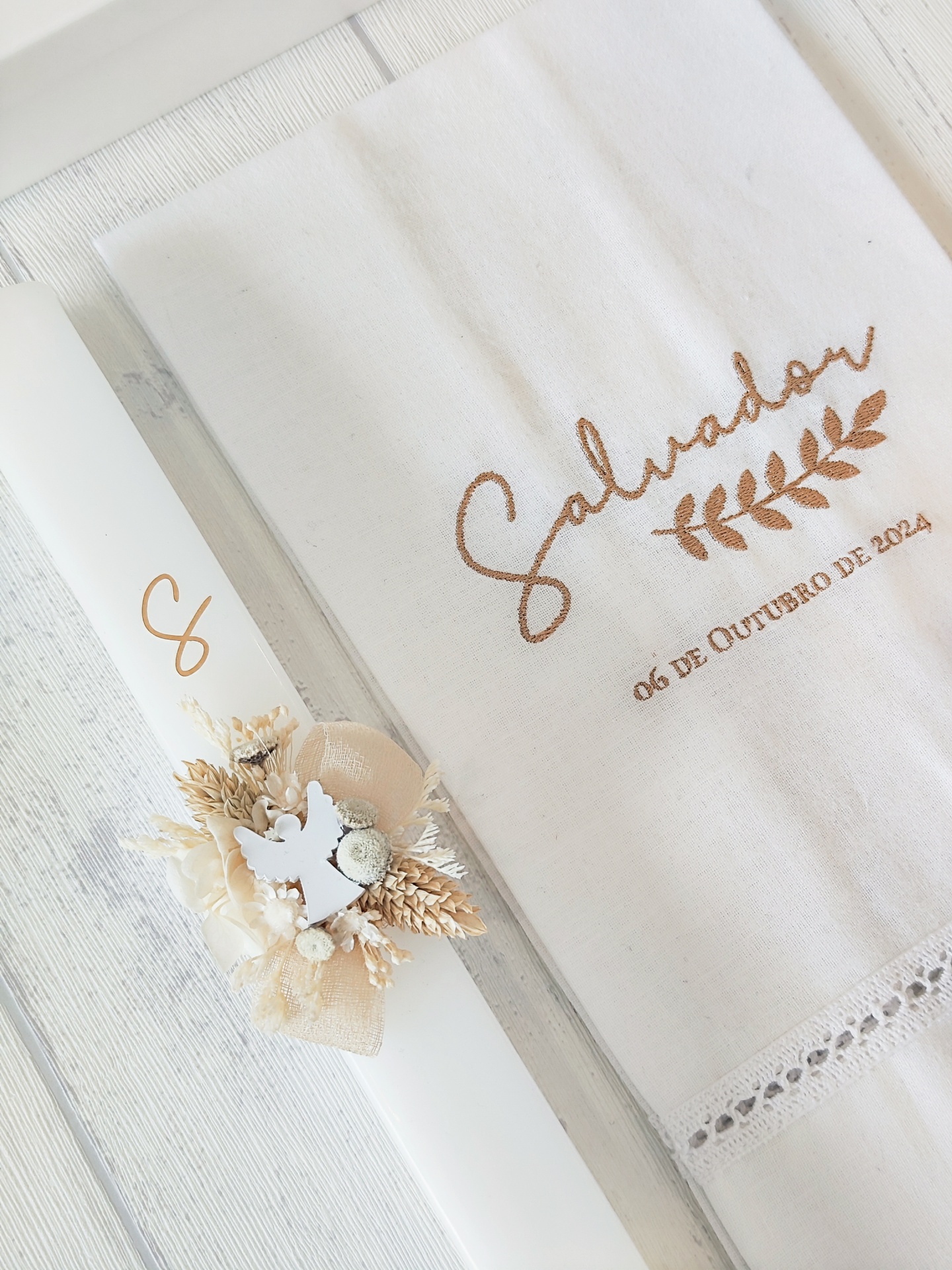 Toalha branca com bordado castanho e vela branca decorada com flores secas e laço bege