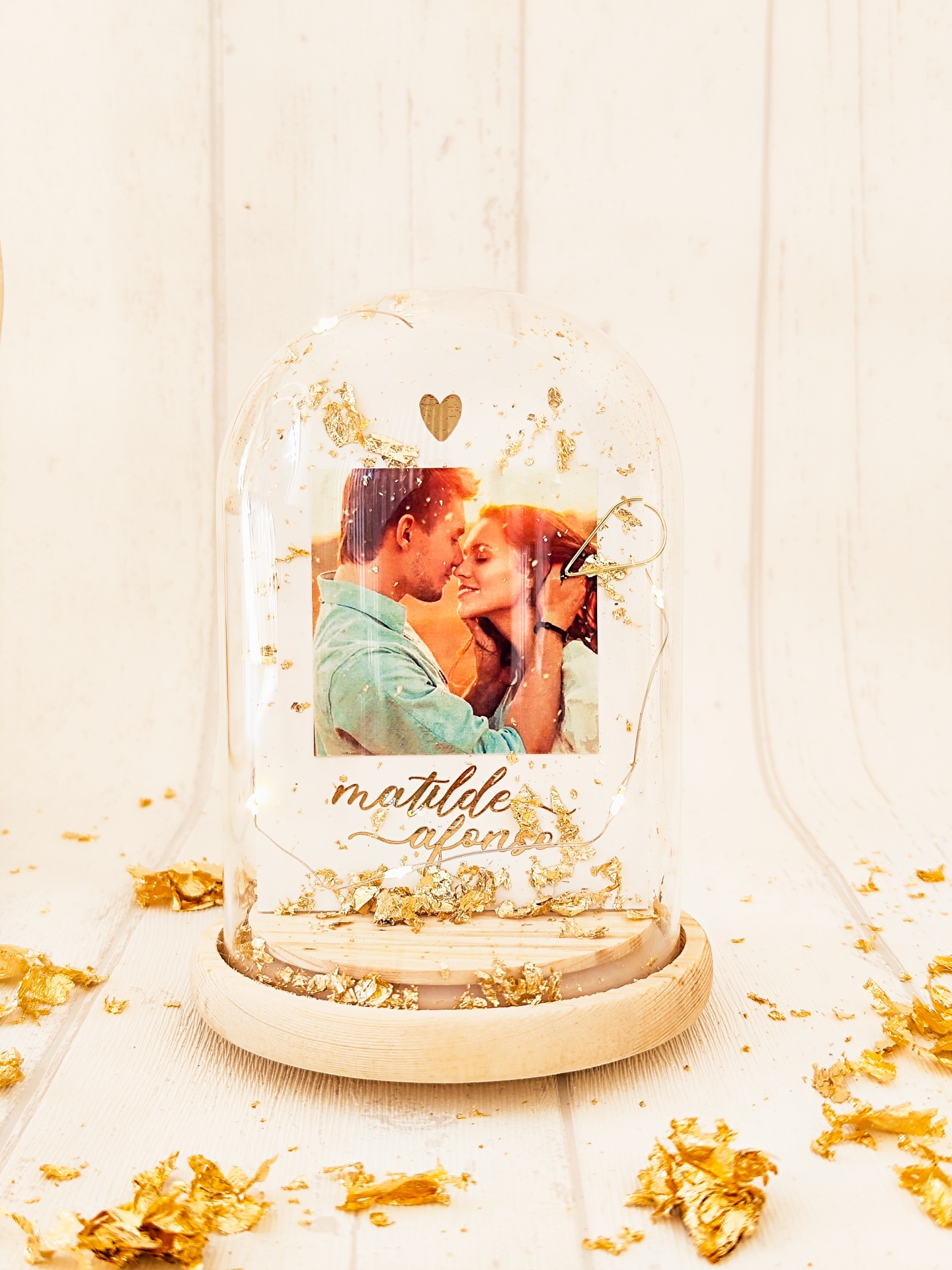 Globo de vidro com fotografia de casal, folhas douradas e texto em madeira clara