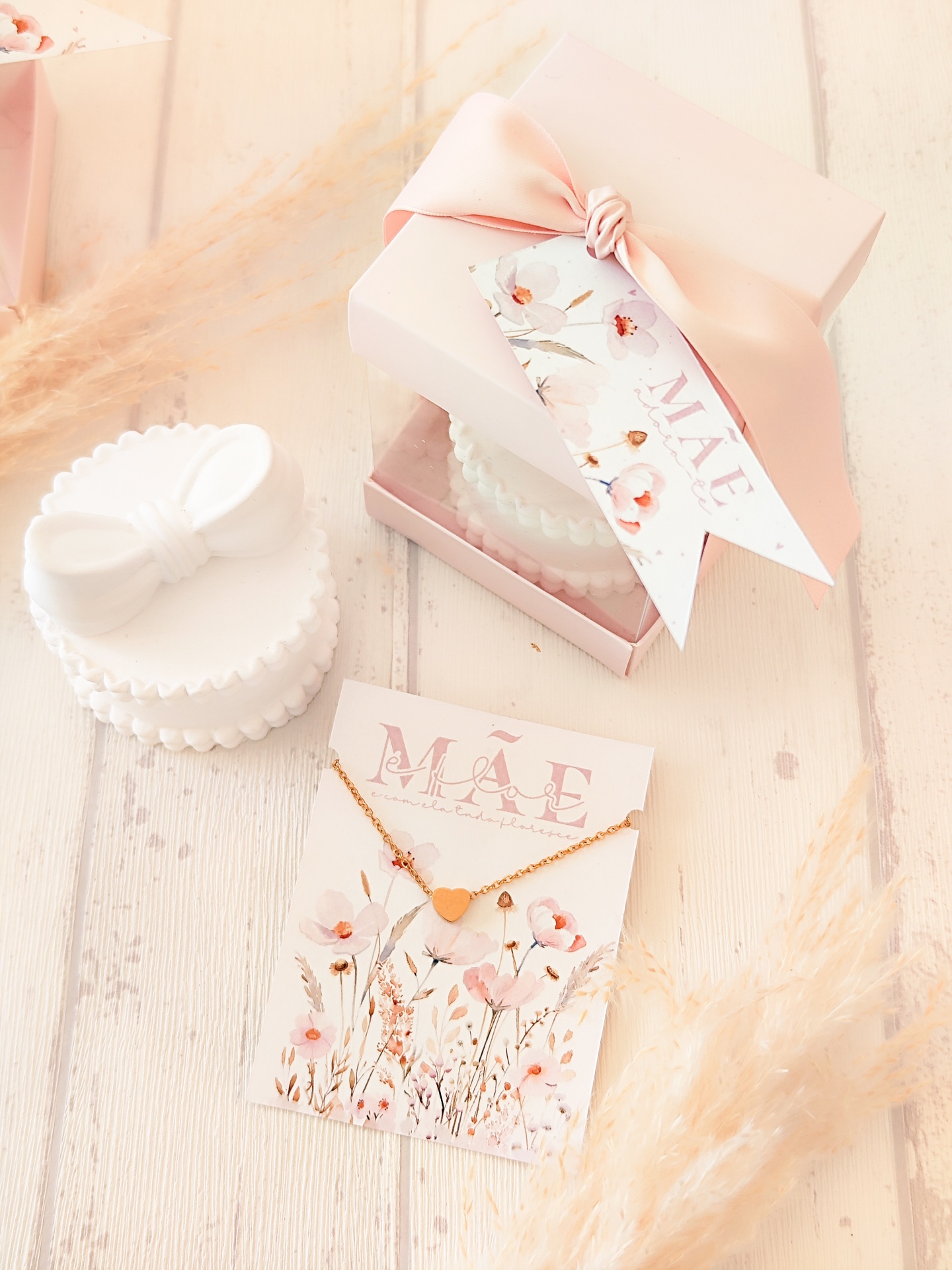 Colar dourado coração com embalagem de oferta rosa e cartão MÃE em superfície clara