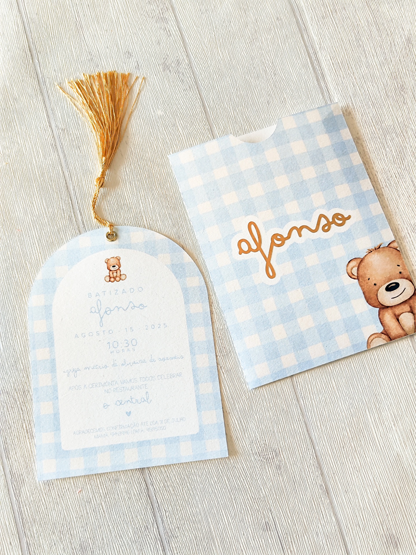 Convite de batizado com padrão azul claro e branco, ursinho e tassel dourado.