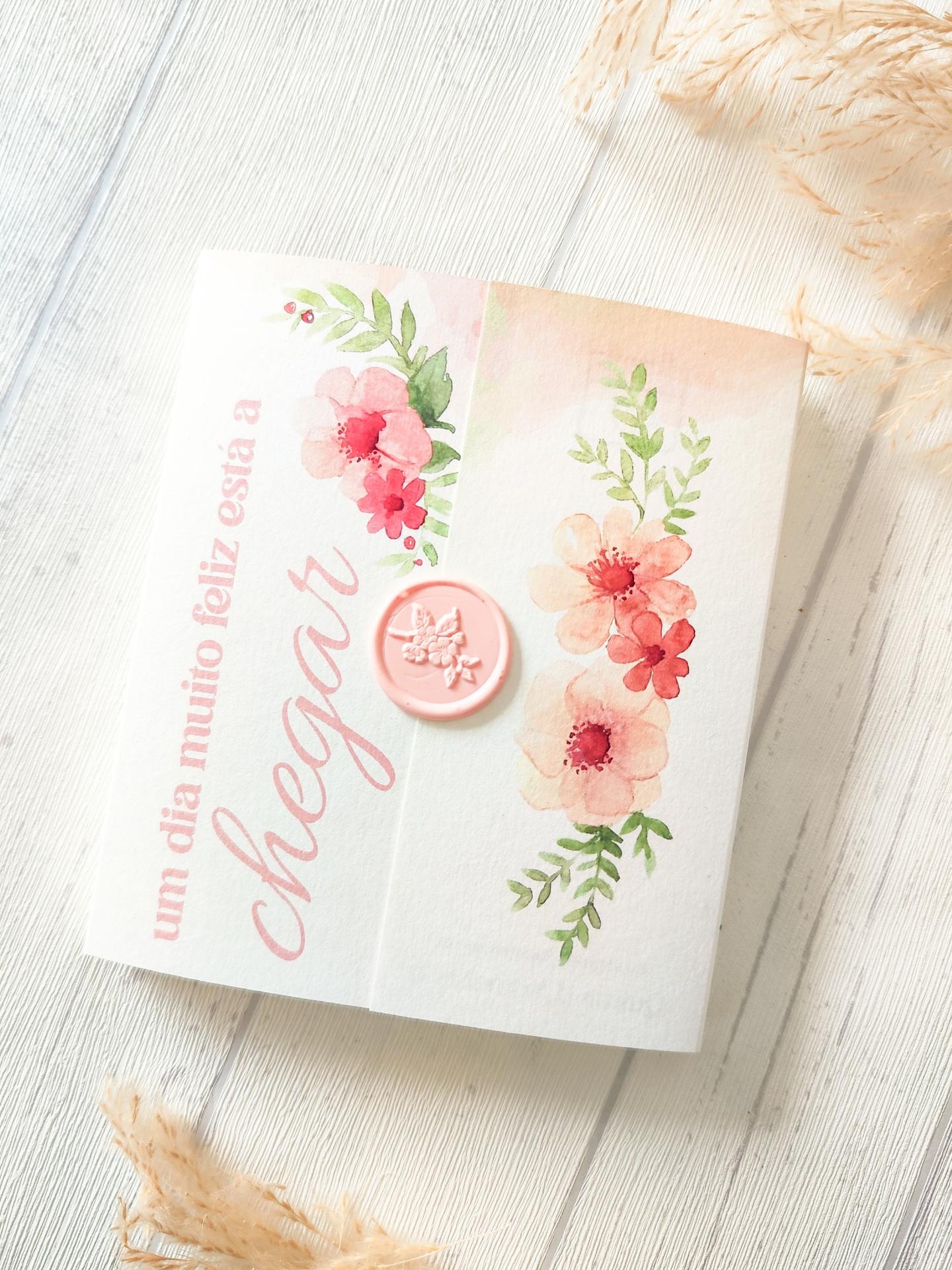 Caixa branca decorada com flores e texto em rosa sobre superfície de madeira clara