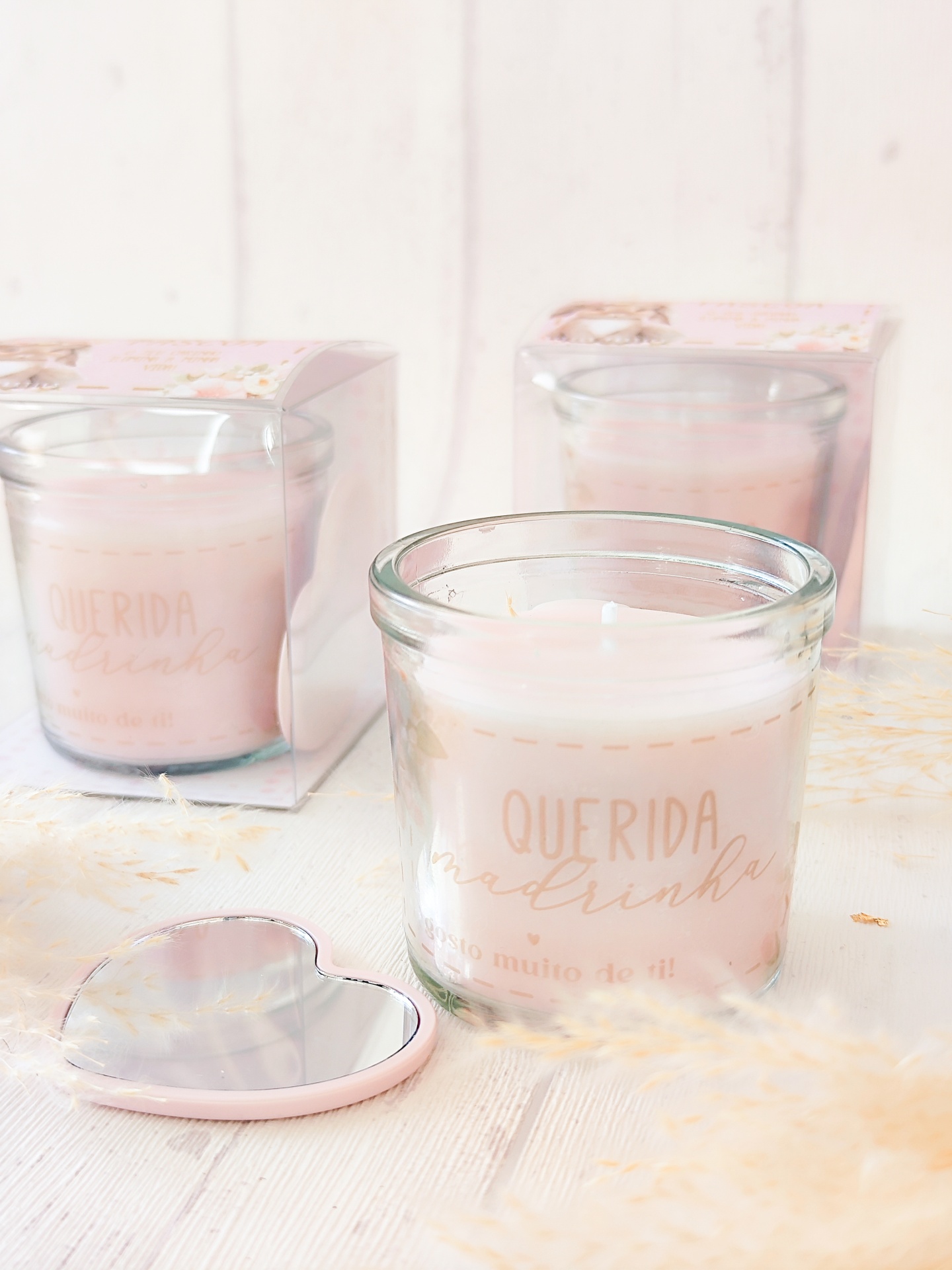 Vela perfumada rosa clara em vidro com tampa em forma de coração e texto 'QUERIDA madrinha'