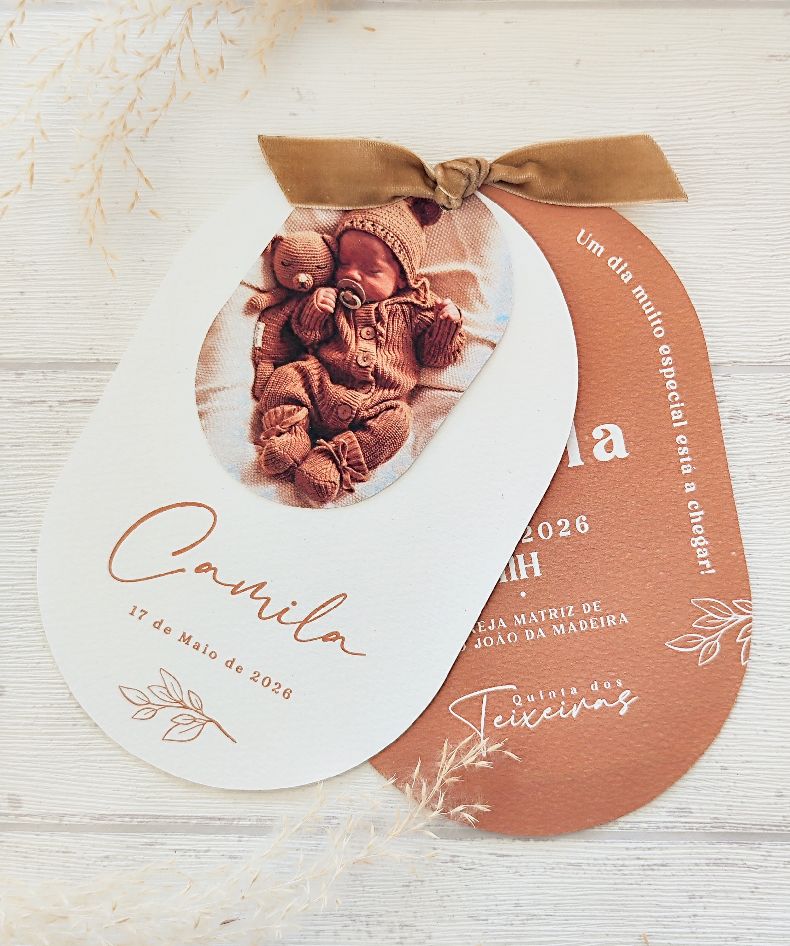 Convites ovais para evento infantil em papel branco e castanho com fotografia de bebé e fita de veludo castanha