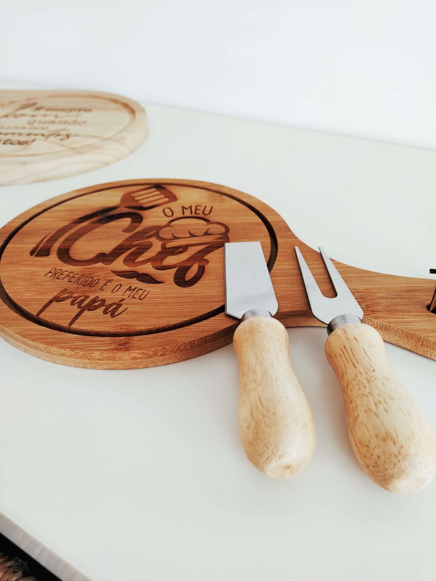 Tábua redonda de madeira com gravação e utensílios para queijo com cabos de madeira