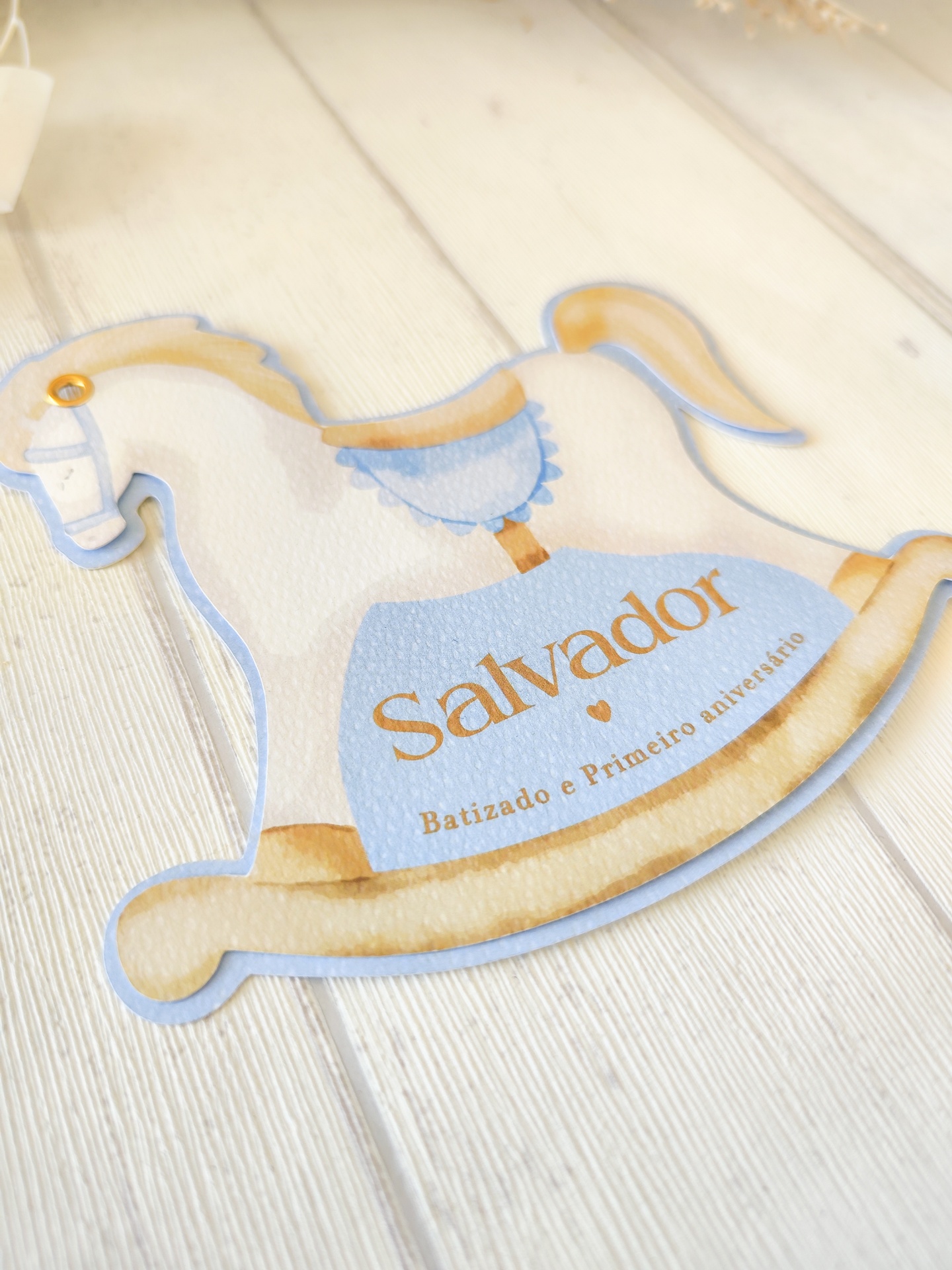 Etiqueta cavalo de balanço azul e dourado com texto 'Salvador Batizado e Primeiro aniversário'