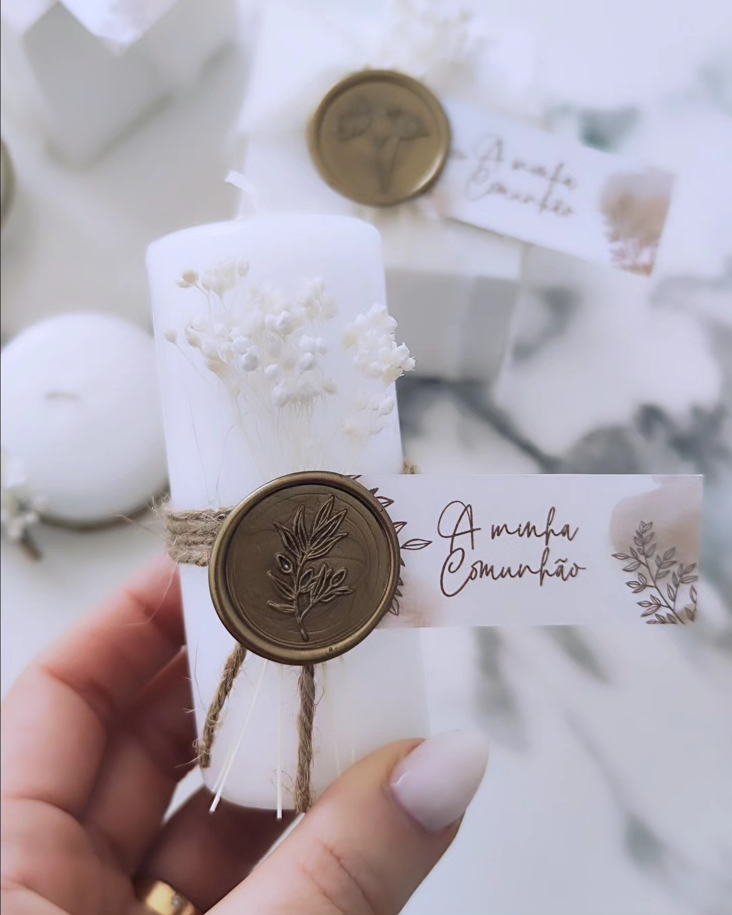 Vela branca decorativa com flores secas e selo de cera com mensagem 'A minha Comunhão'