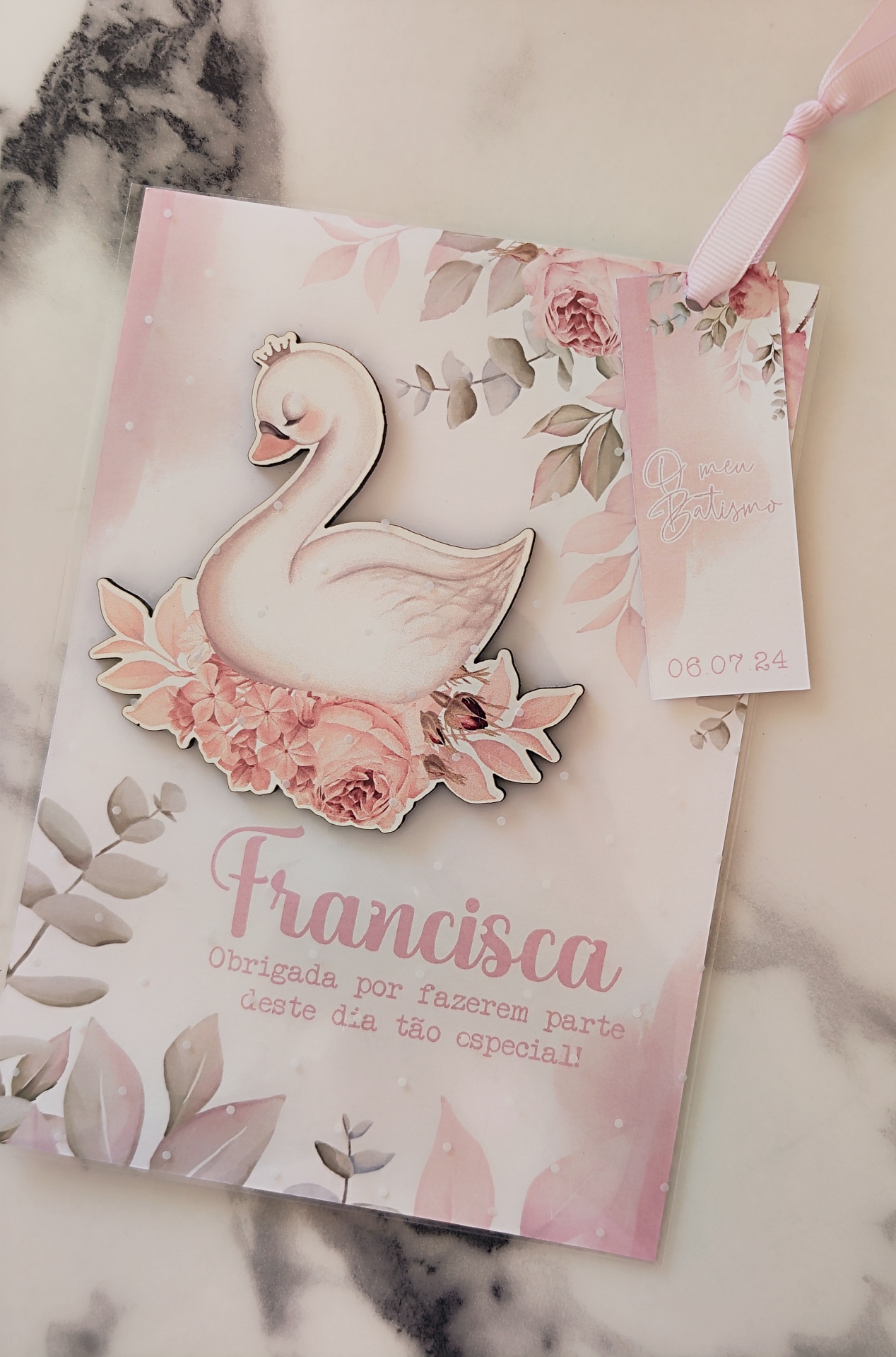 Cartão com cisne branco e flores, e pequeno cartão rosa com data e texto decorativo.