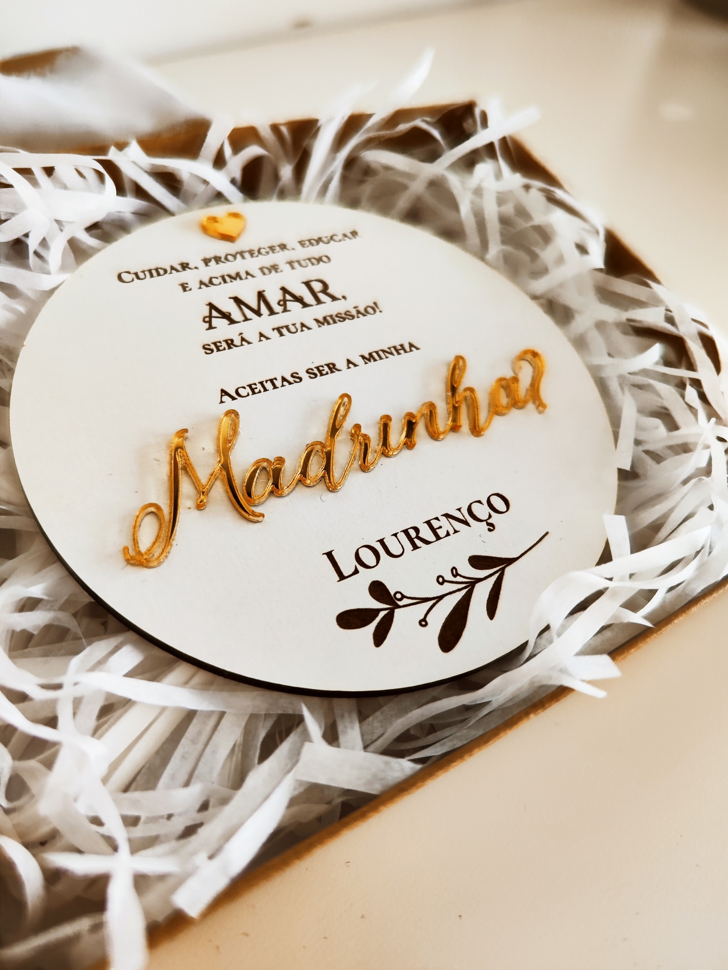 Placa redonda decorativa com texto em português e nome Lourenço embalada com papel de seda