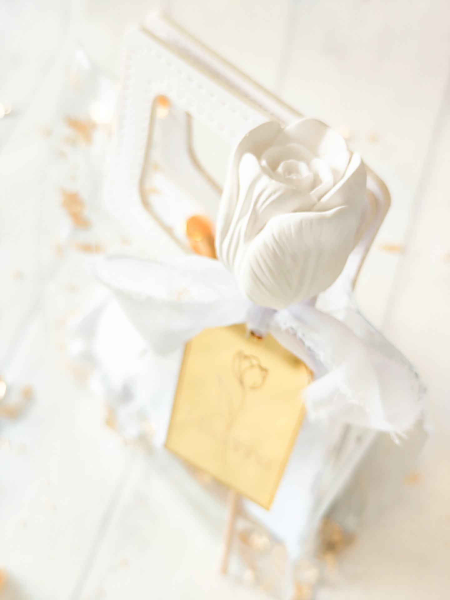 Objeto decorativo rosa branca com fita e placa dourada com palavra HOME