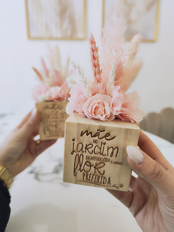 Mini vaso decorativo em madeira com flores artificiais rosas e bege, com texto gravado.
