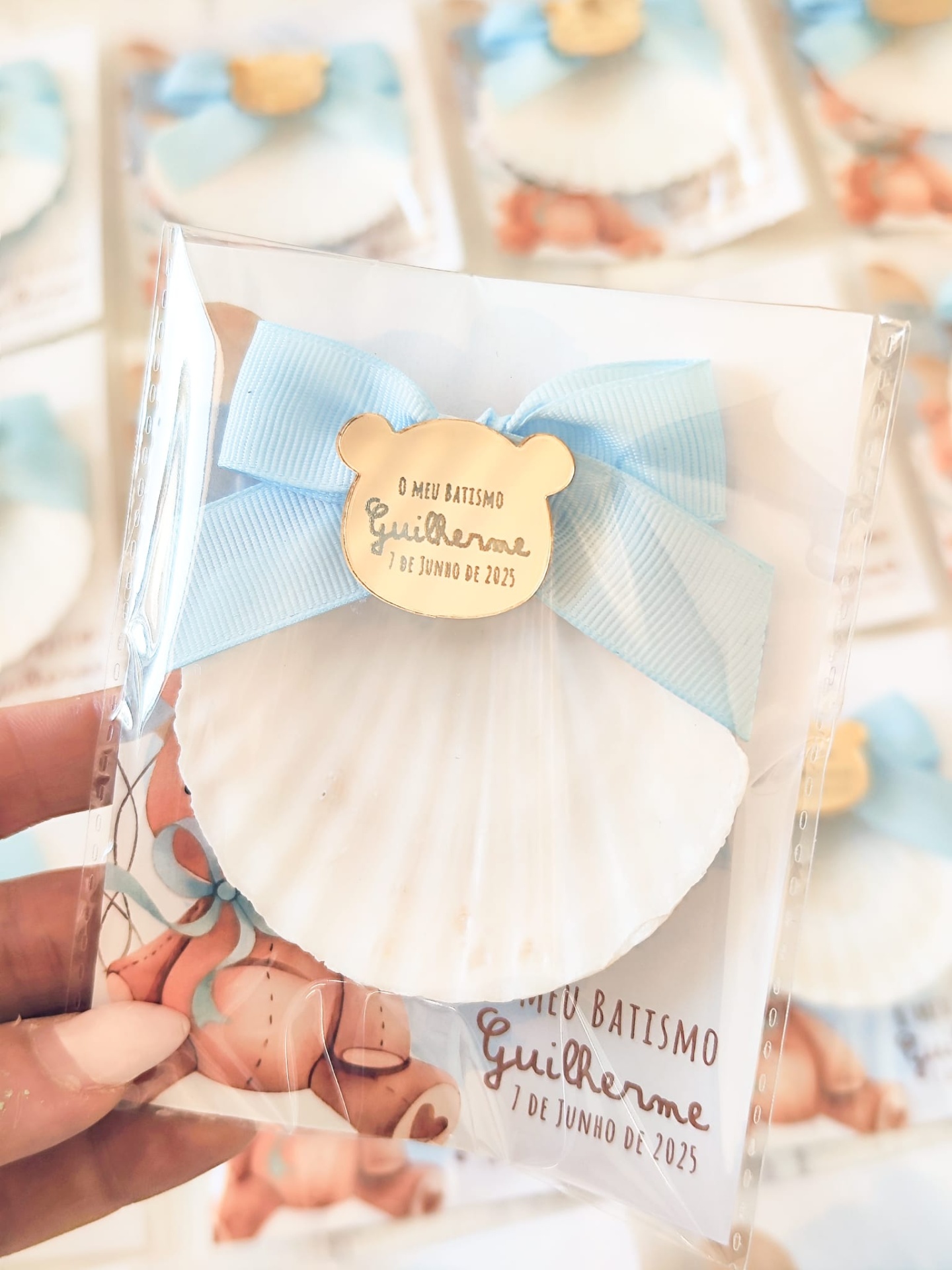 Concha decorativa branca com laço azul e placa de madeira com texto para batismo