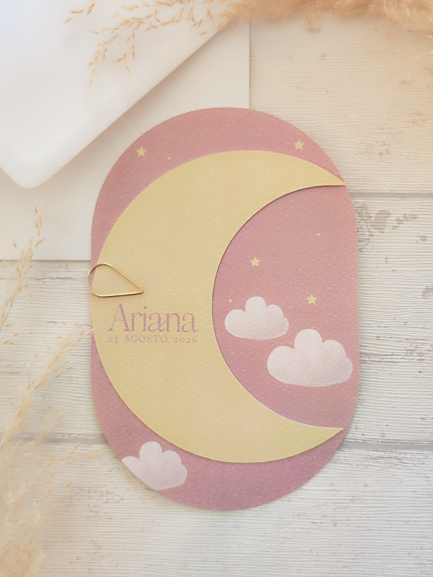 Convite oval com lua amarela, céu rosa, estrelas e nuvens, texto Ariana 23 AGOSTO 2026
