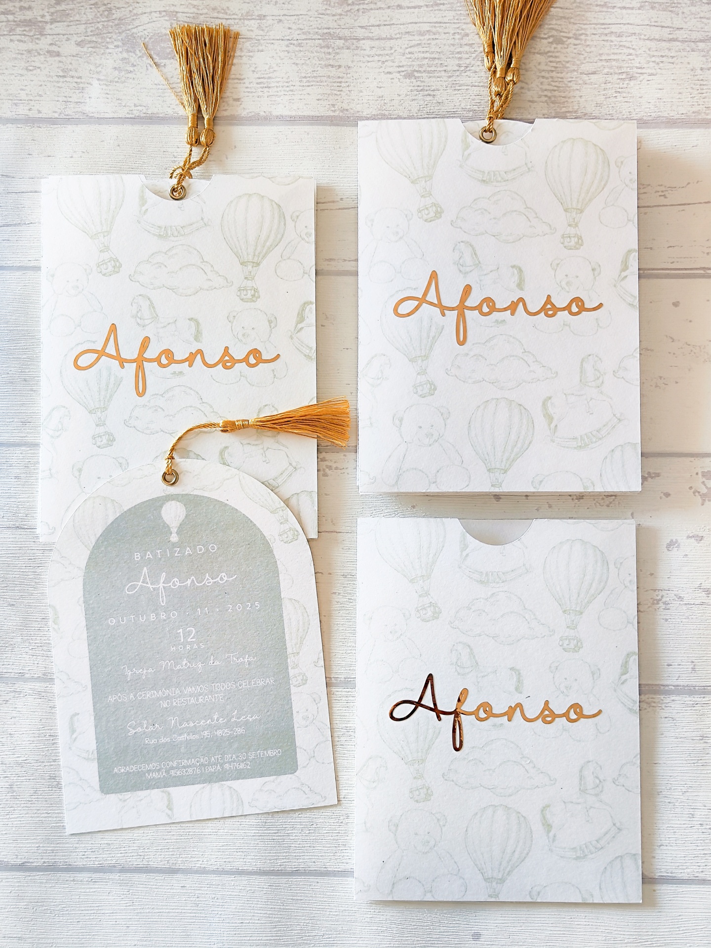 Convites de batizado em cartão branco com padrão cinza e nome Afonso em dourado com tassel.