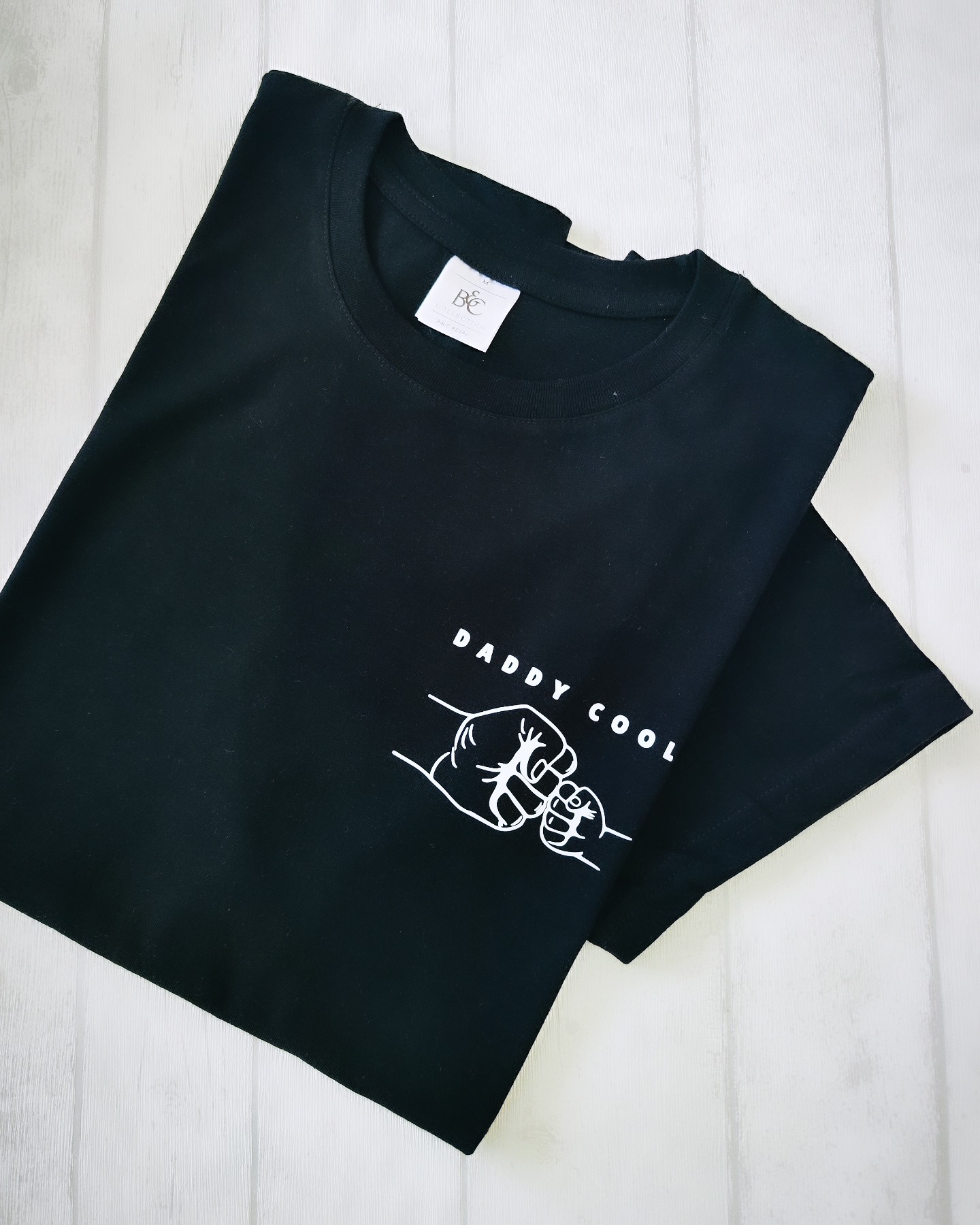 T-shirt preta com estampado branco 'DADDY COOL' e punhos a dar 'fist bump'