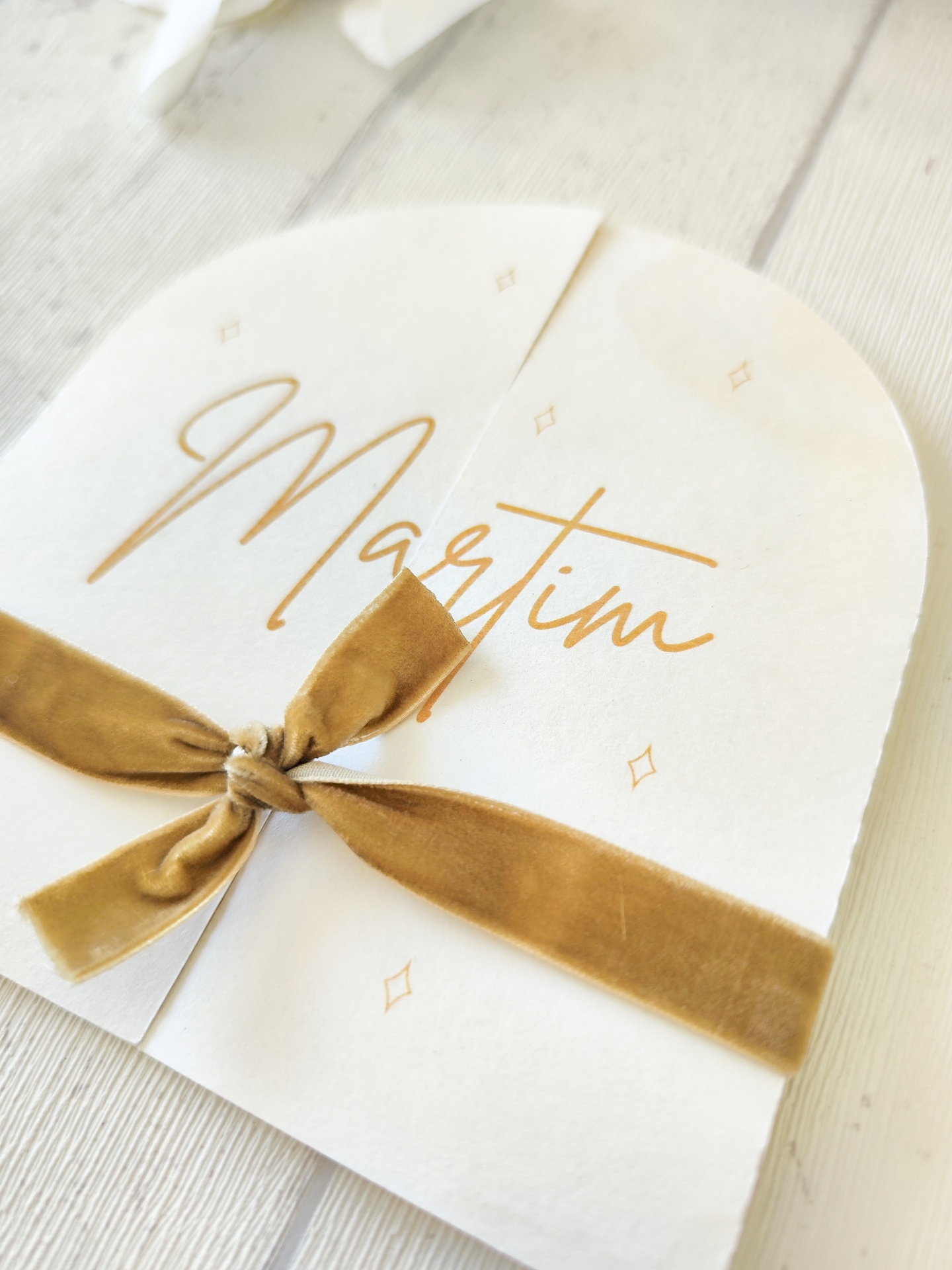 Convite branco com texto Martim em dourado e fita de veludo castanha