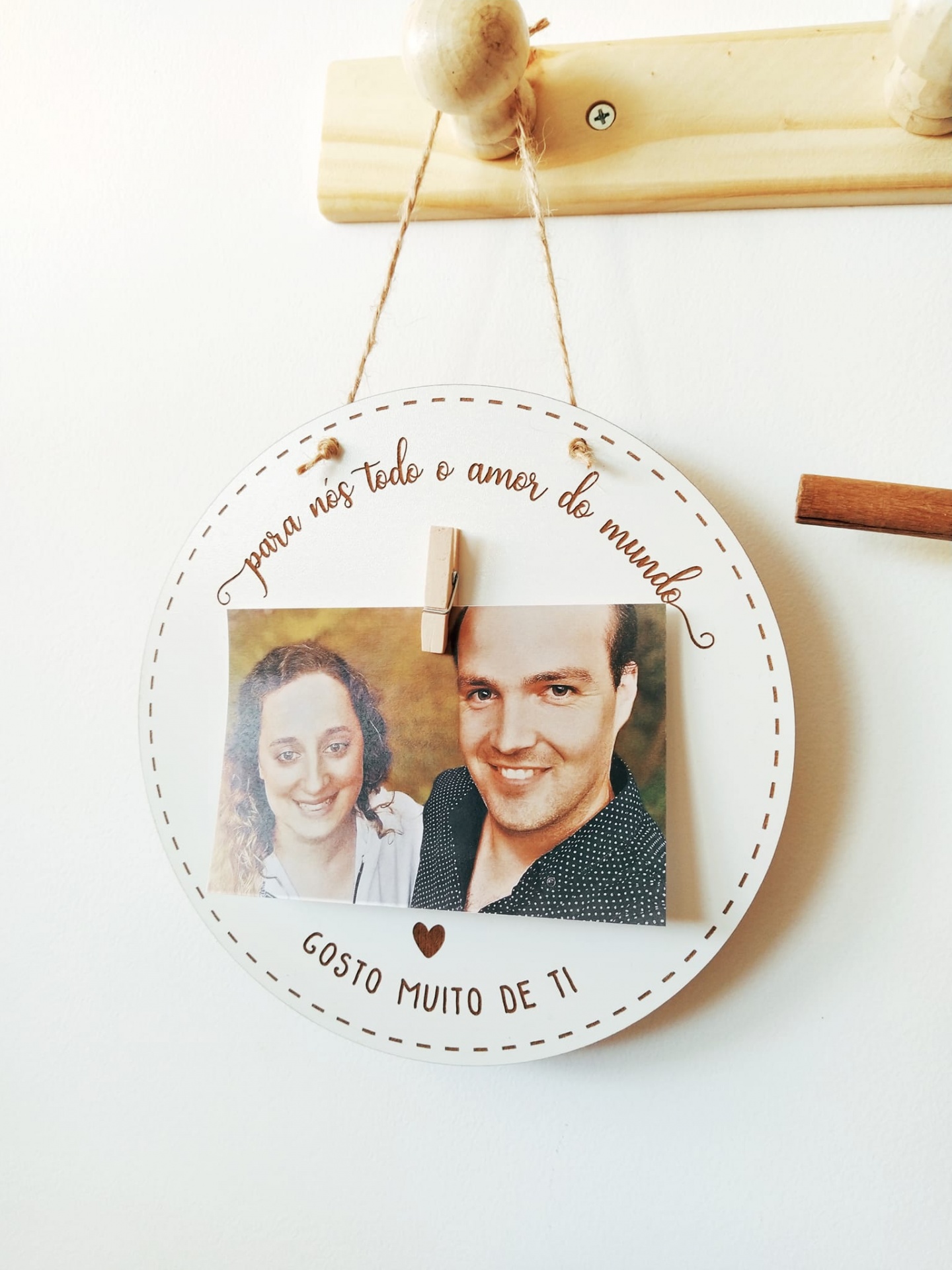 Placa decorativa redonda com fotografia e texto em português pendurada na parede