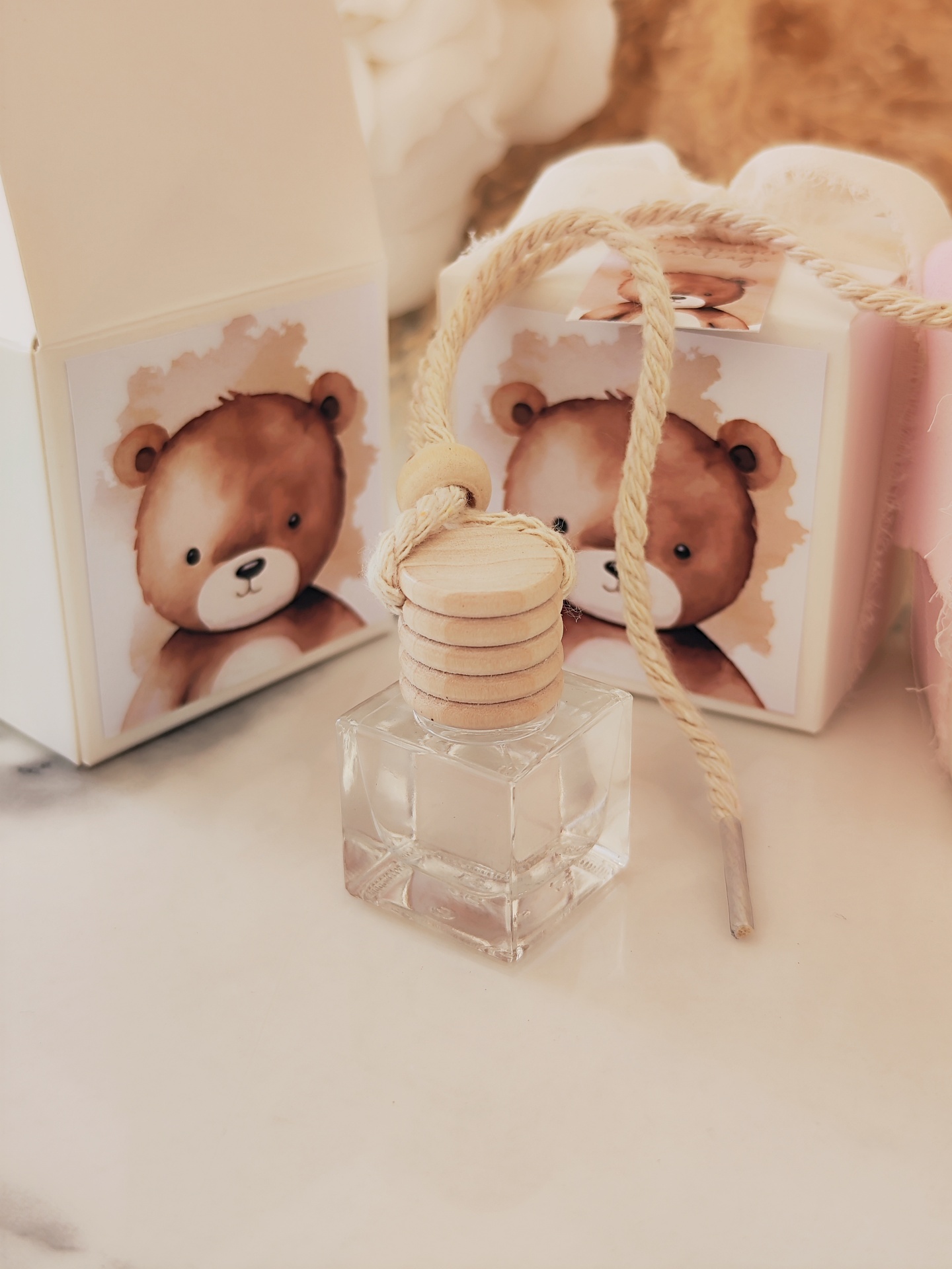 Frasco quadrado transparente com tampa de madeira e cordão, duas caixas com desenho de urso castanho
