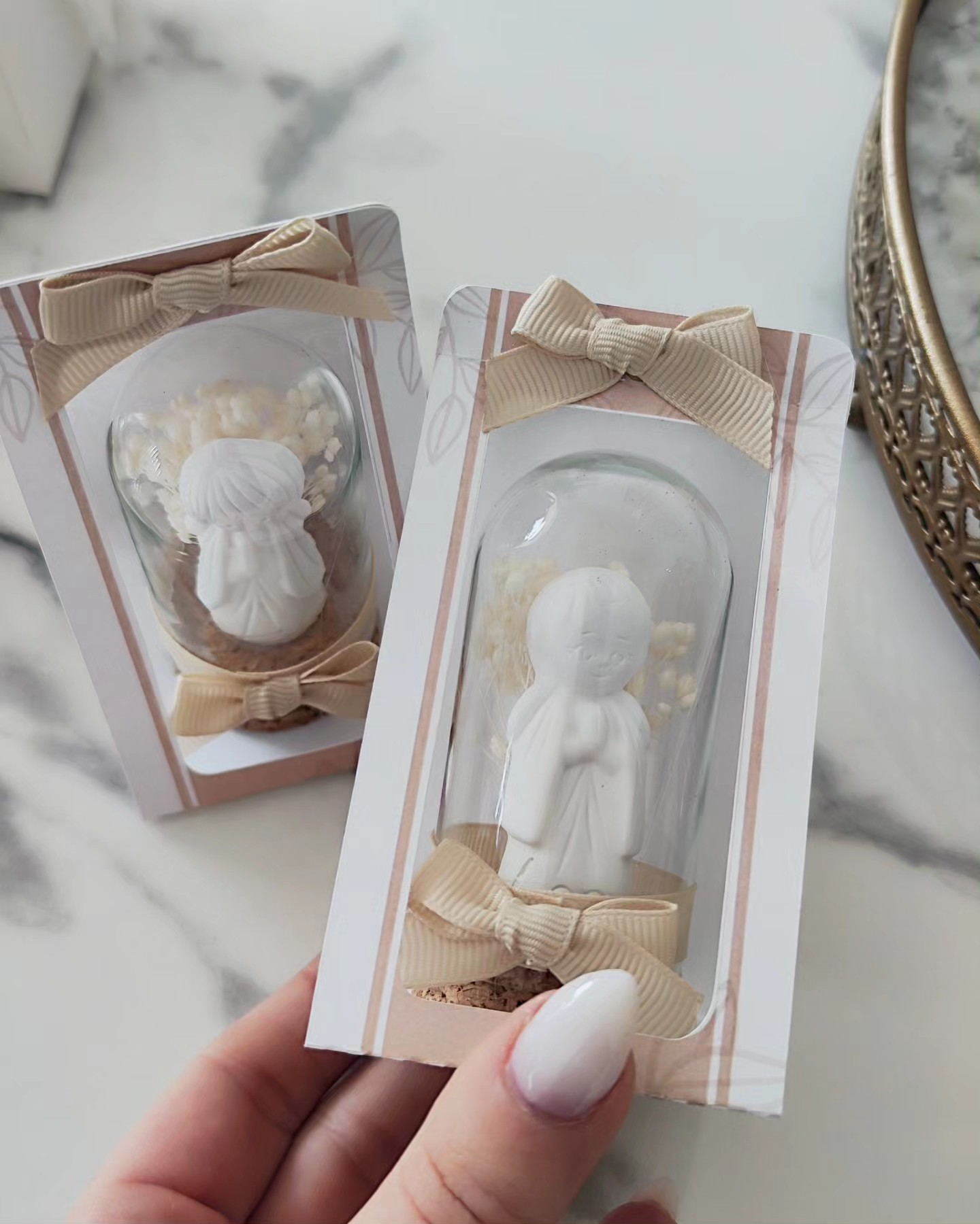 Pequenos anjos de resina branca em caixas transparentes com laços bege