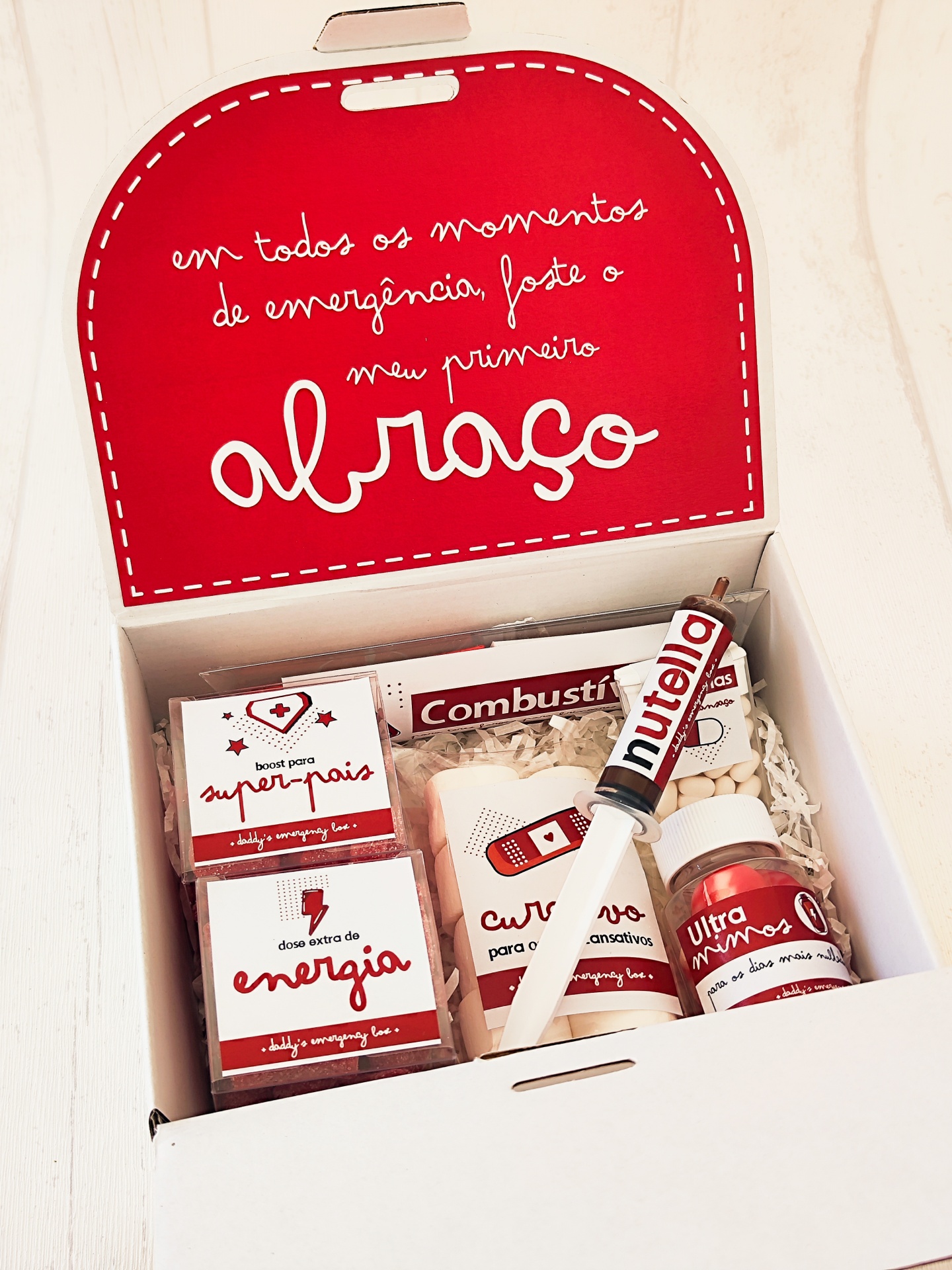 Caixa branca aberta com produtos de cuidados pessoais e caneta Nutella em fundo vermelho.