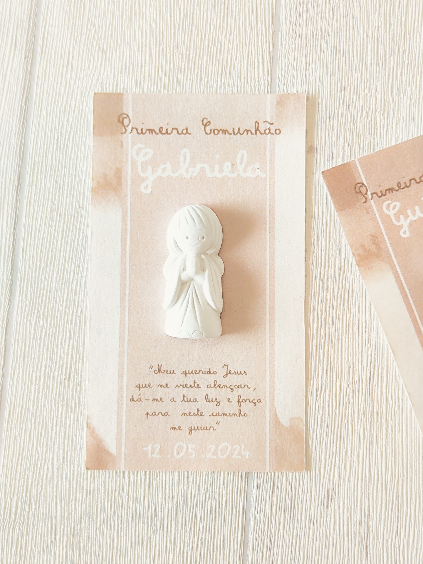 Cartão para Primeira Comunhão com figura branca de criança em oração e texto em castanho e branco sobre fundo bege