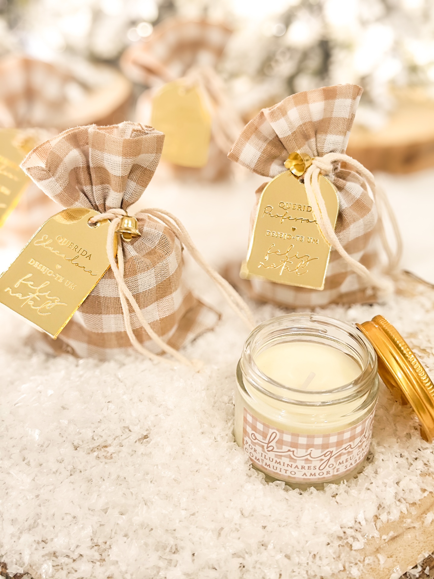 Vela em vidro com tampa dourada e sacos de tecido xadrez bege com etiquetas douradas