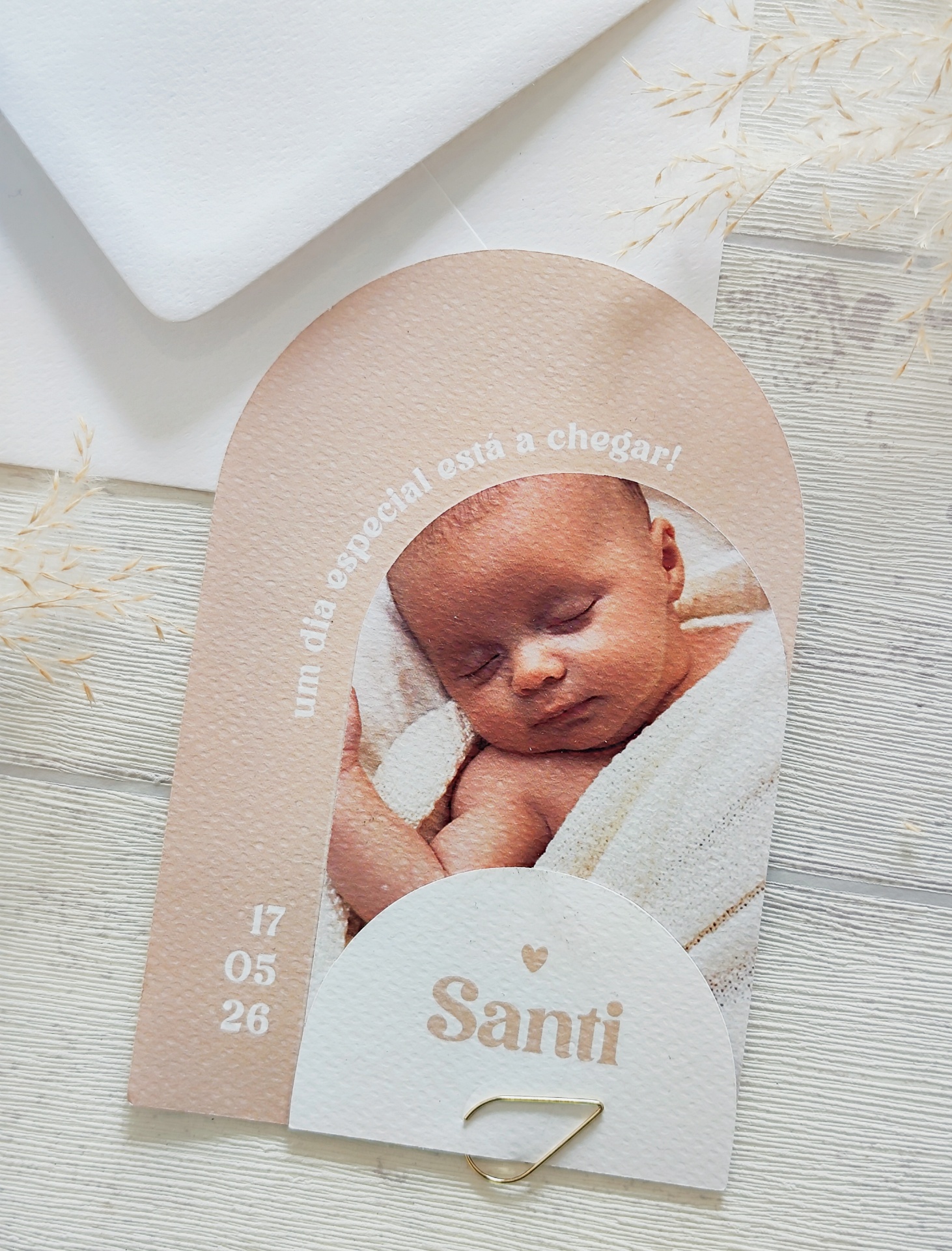Convite em papel texturizado com foto de bebé e texto em português.
