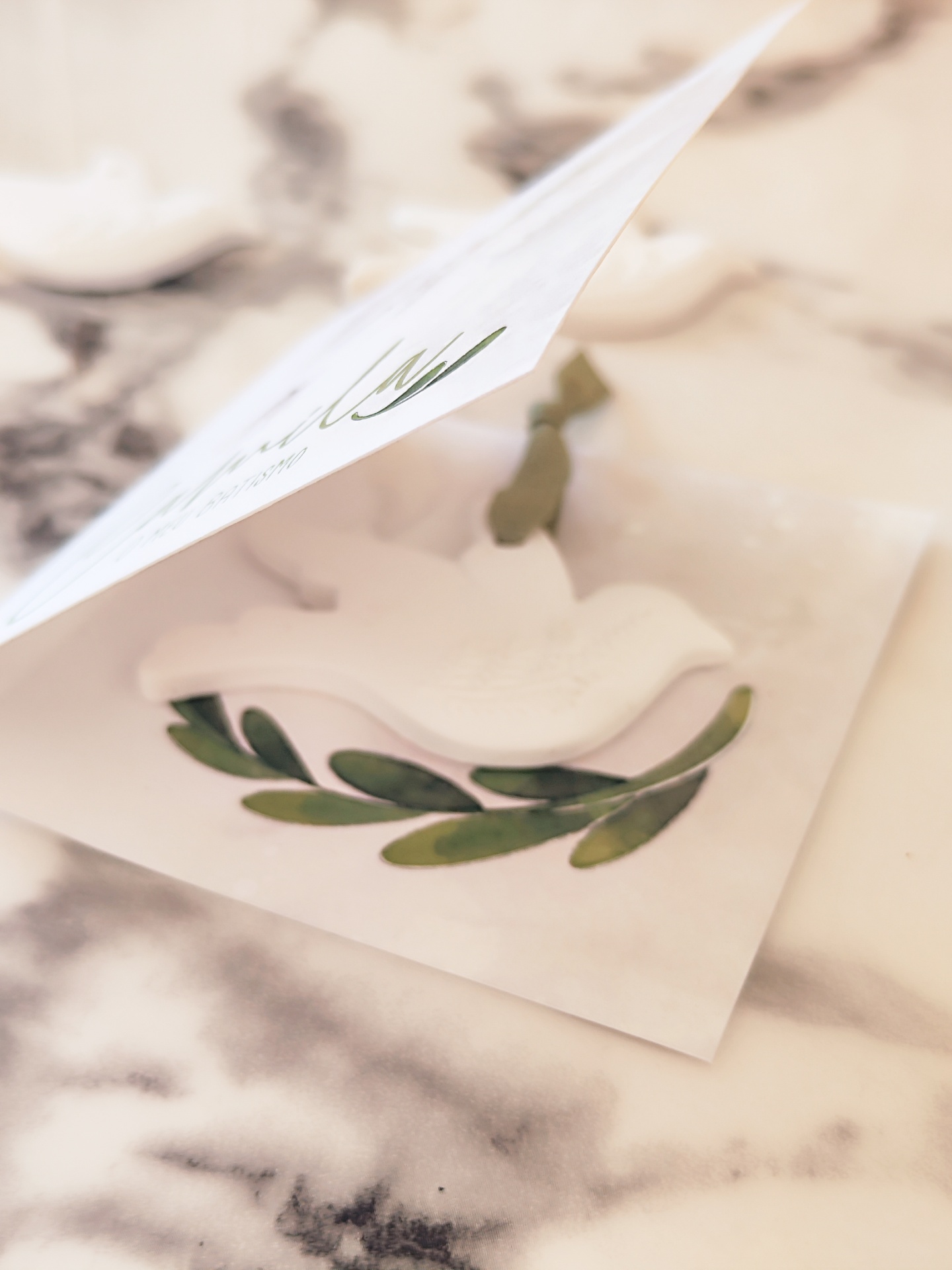 Cartão branco com relevo de pomba sobre ramo de folhas verdes