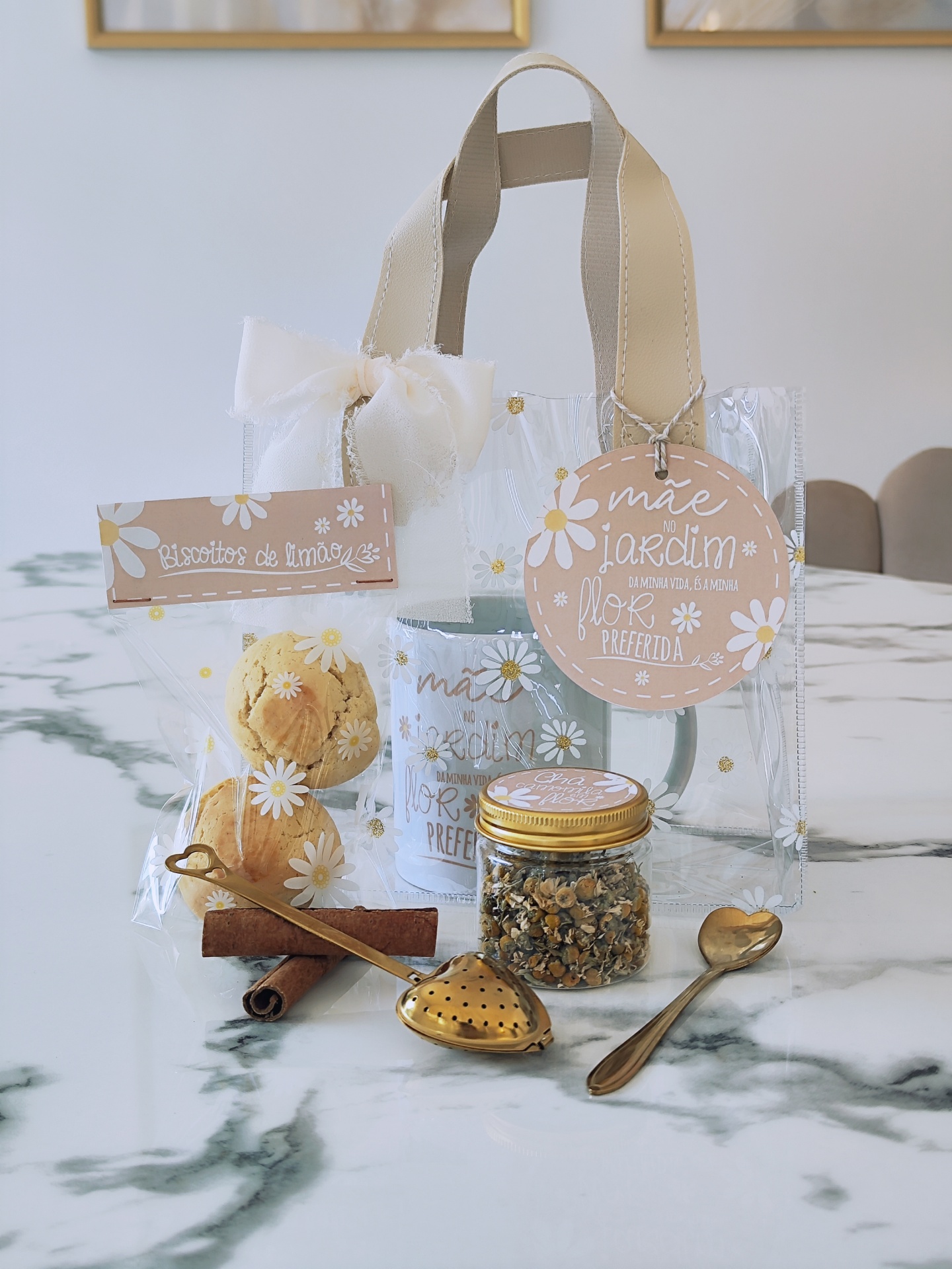 Conjunto de chá com caneca azul, biscoitos, frasco com camomila, colher e infusor, em saco transparente com alças e laço branco