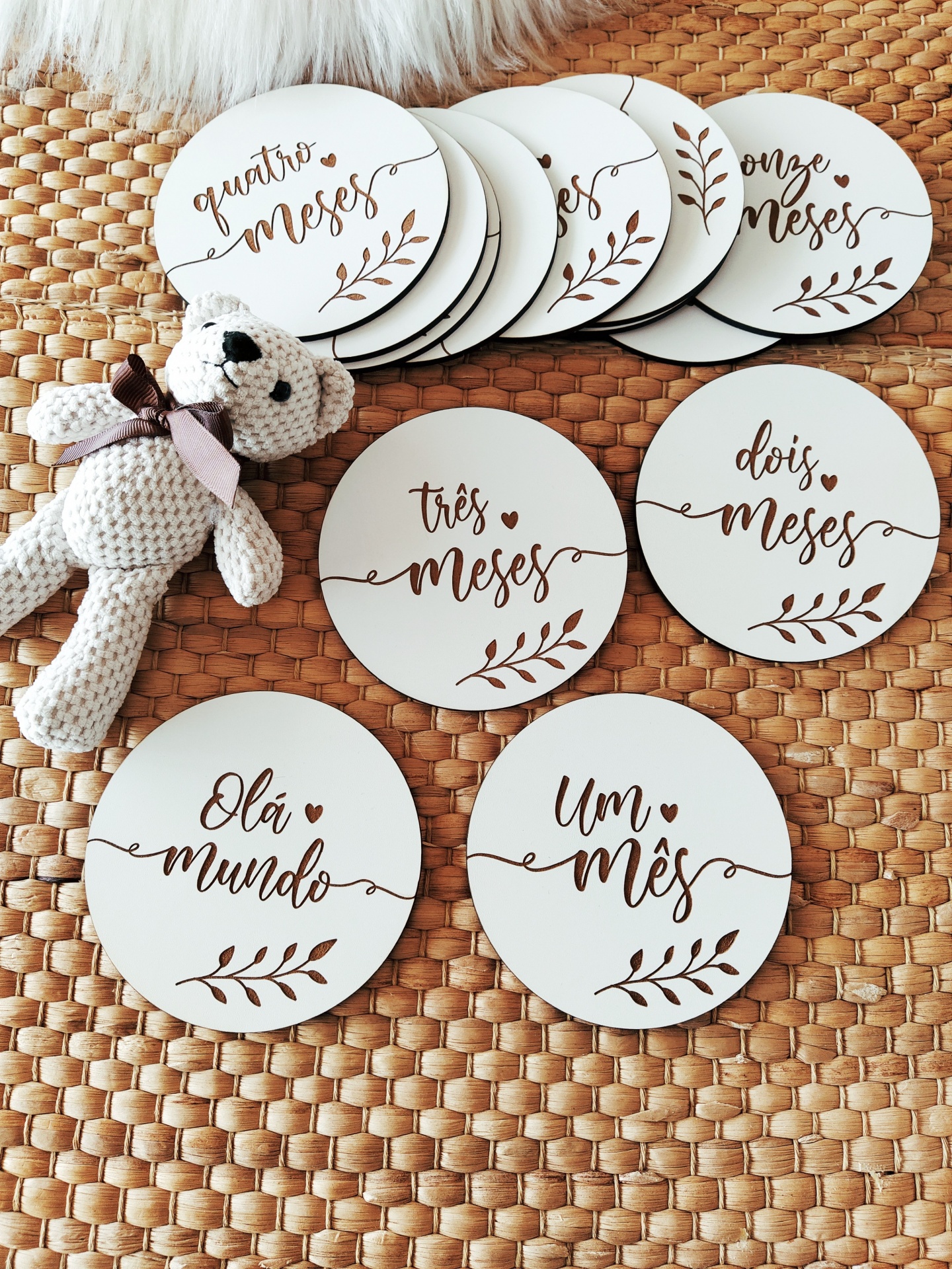 Placas redondas brancas com texto em caligrafia castanha e boneco de crochê sobre tapete trançado.