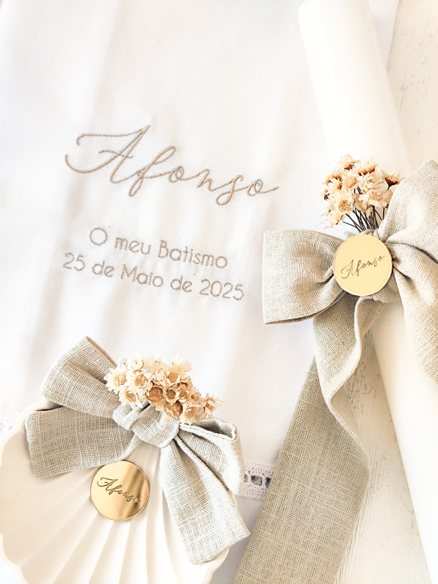 Toalha de batismo branca com bordados e velas decoradas com laços bege e flores secas