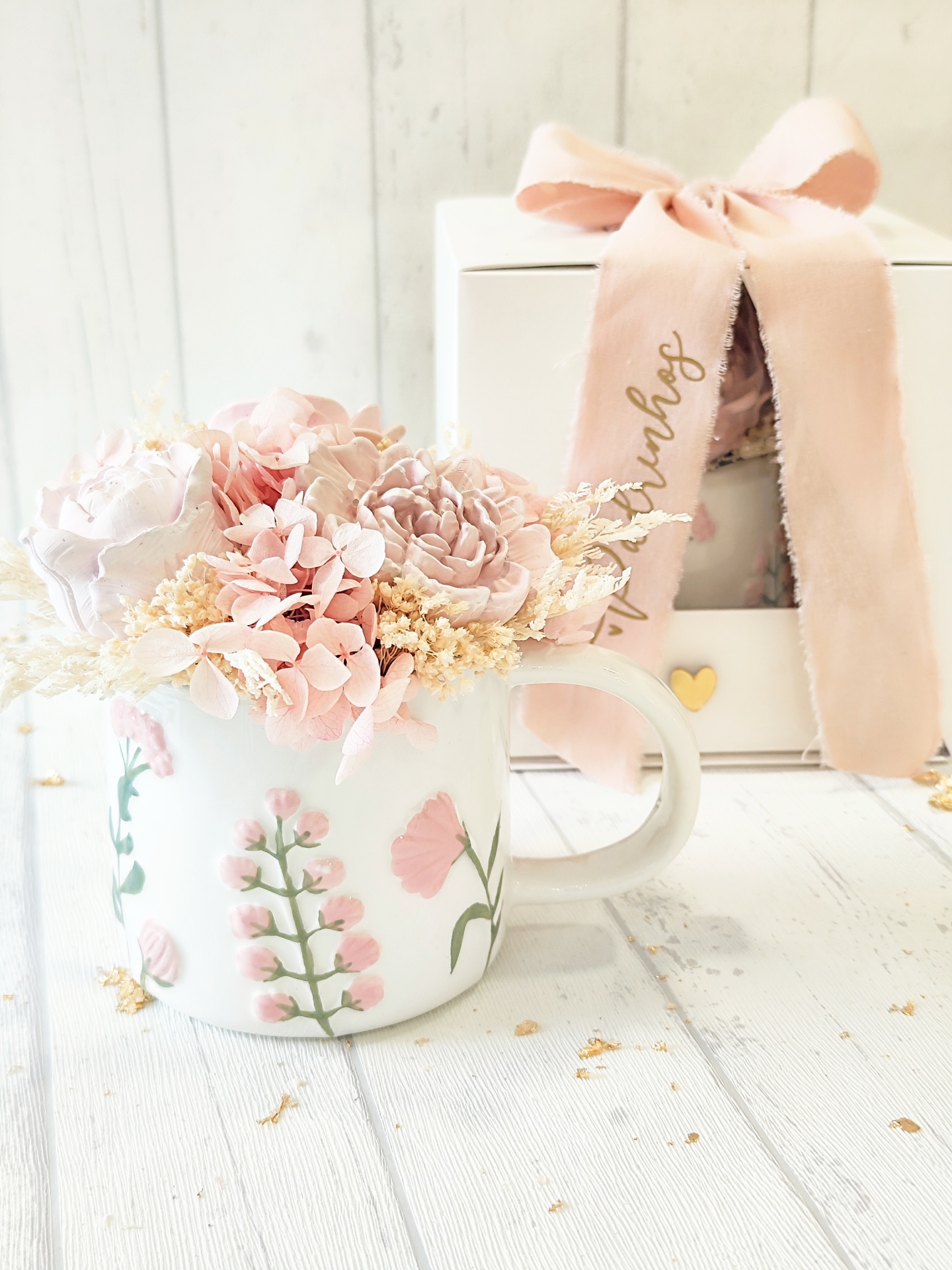 Caneca branca com flores pintadas e arranjo floral artificial rosa dentro