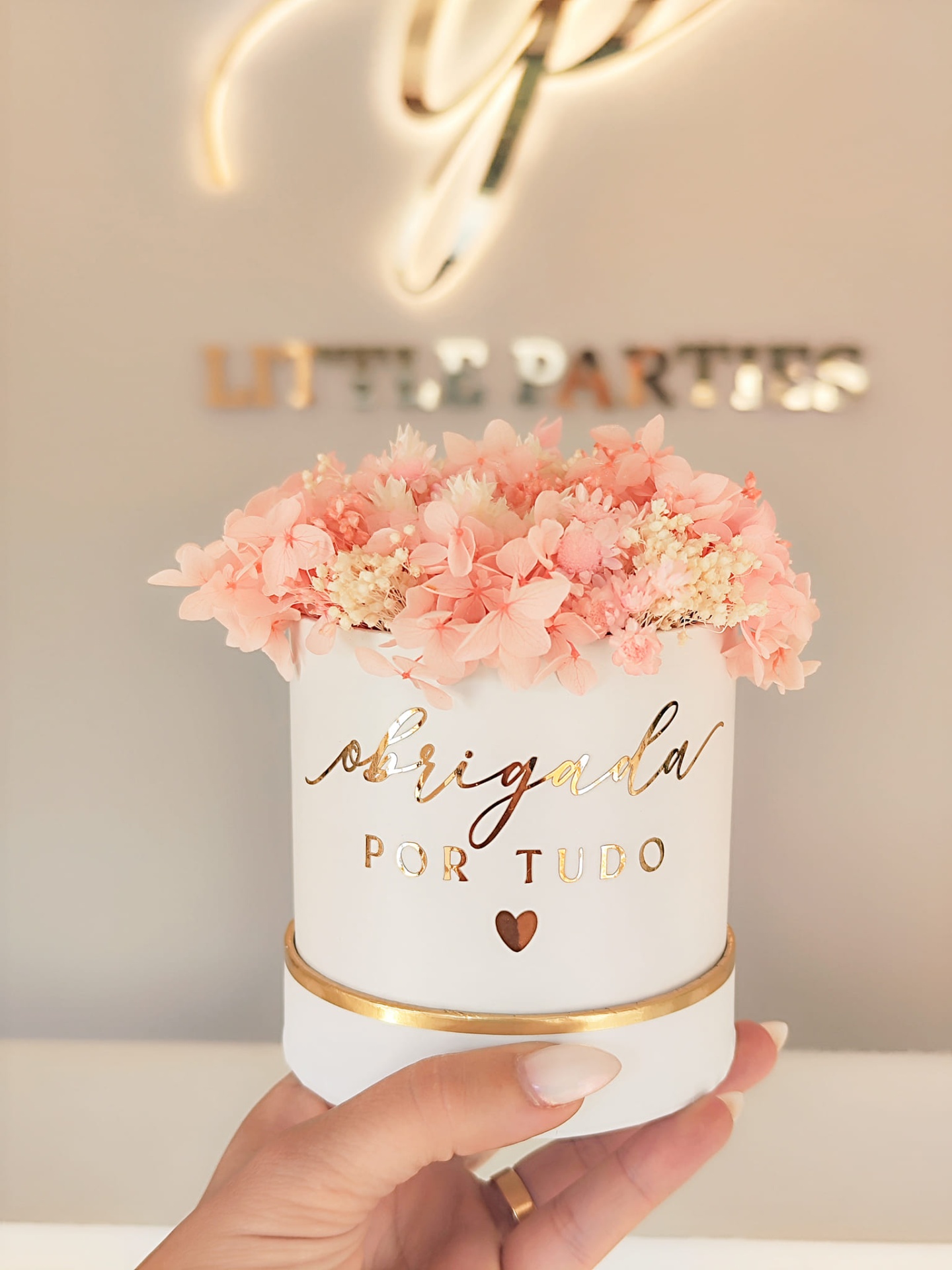 Vaso branco com flores cor de rosa e texto dourado 'obrigada POR TUDO'