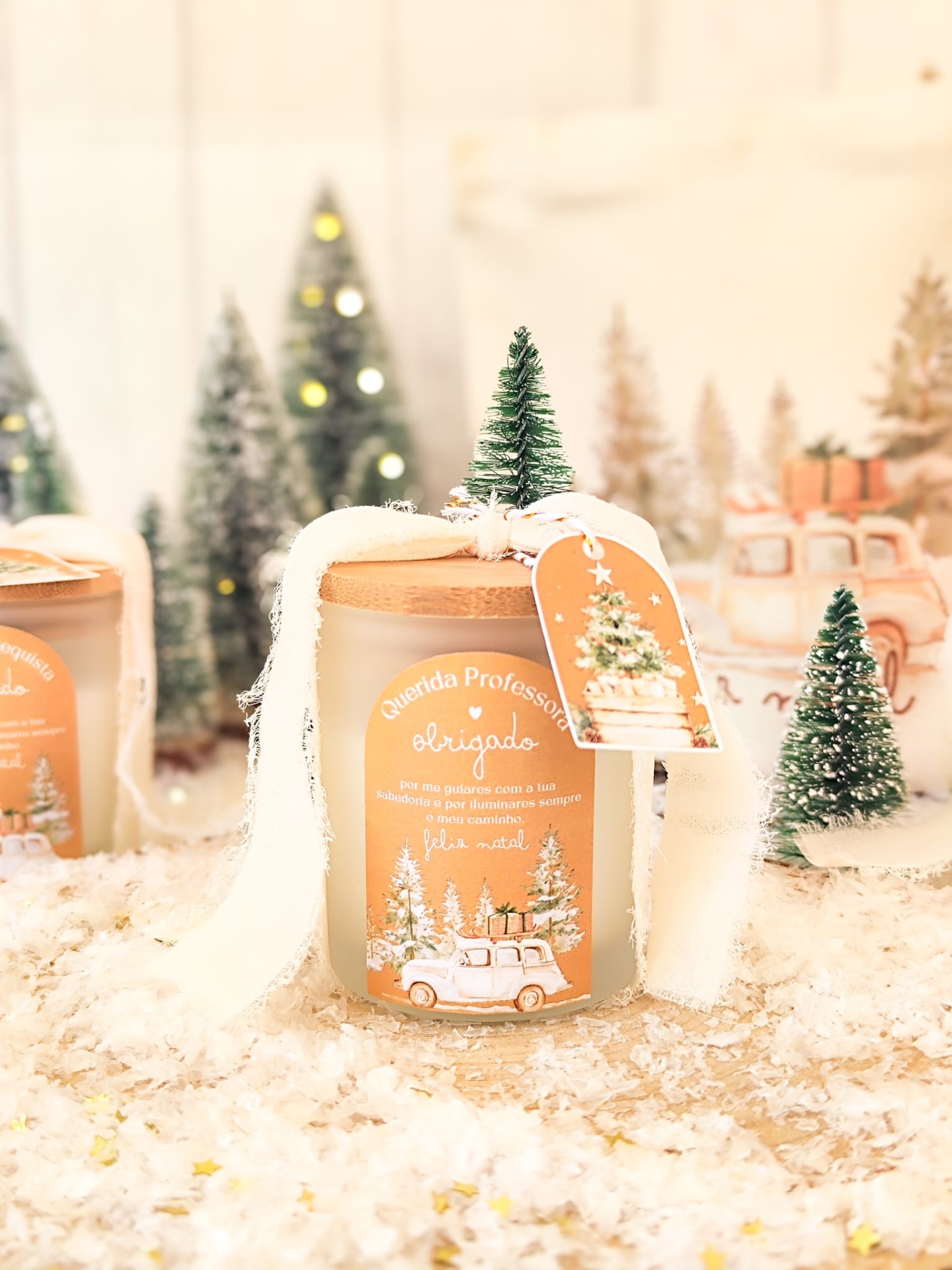 Vela decorativa natalícia com mini pinheiro e etiqueta laranja em jarro de vidro fosco.