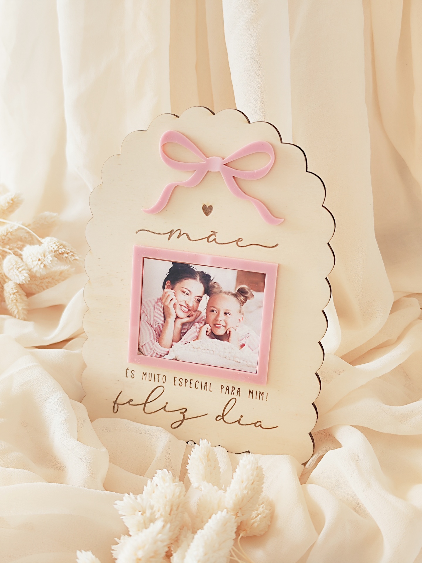 Moldura de madeira clara em forma de nuvem com laço rosa e foto de mãe e filha