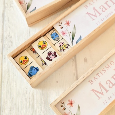 Conjunto de dominós de madeira com desenhos de animais e caixas de madeira claras com texto de batismo