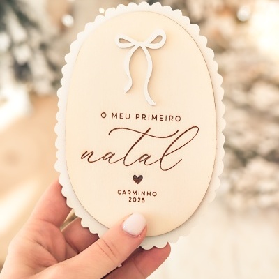 Enfeite oval de madeira com texto gravado sobre fundo desfocado