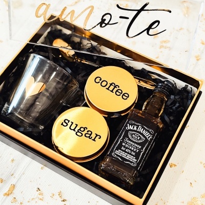 Conjunto regalo com copo, frascos, garrafa e colher em caixa preta com tampa transparente e texto amo-te