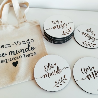 Saco de tecido bege com texto e discos brancos redondos para meses de bebé com letras pretas