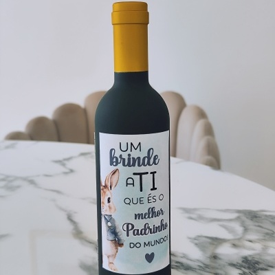 Garrafa decorativa com rótulo e desenho de coelho, tampada em amarelo, sobre mesa de mármore.