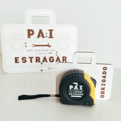 Fita métrica preta e amarela com embalagem branca em forma de maleta com texto em castanho
