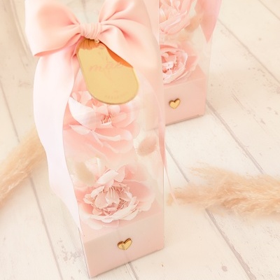 Embalagem transparente com flores cor-de-rosa, laço rosa e etiqueta dourada