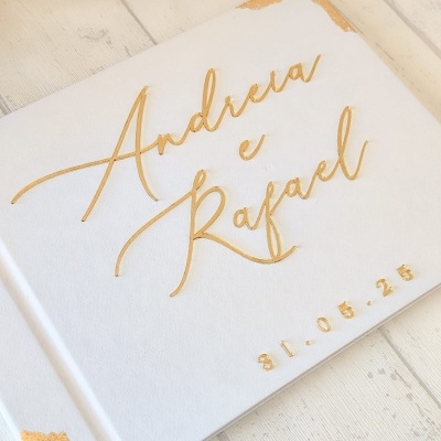 Livro branco com nomes Andreia e Rafael em dourado e data 31.05.25