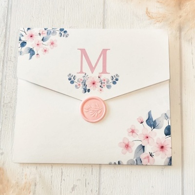 Envelope branco com flores rosas e azuis, selo de cera rosa e letra M