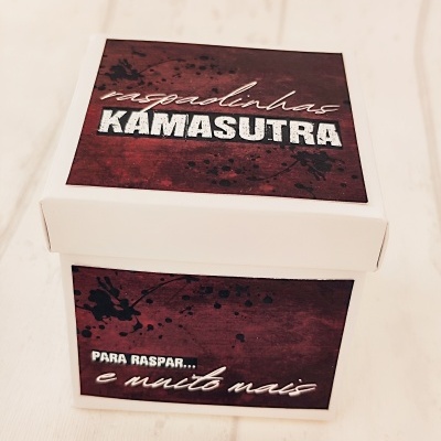 Caixa branca para raspar com texto KAMASUTRA e frases promocionais.