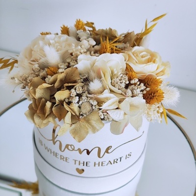 Arranjo de flores secas em vaso branco com frase dourada sobre espelho redondo